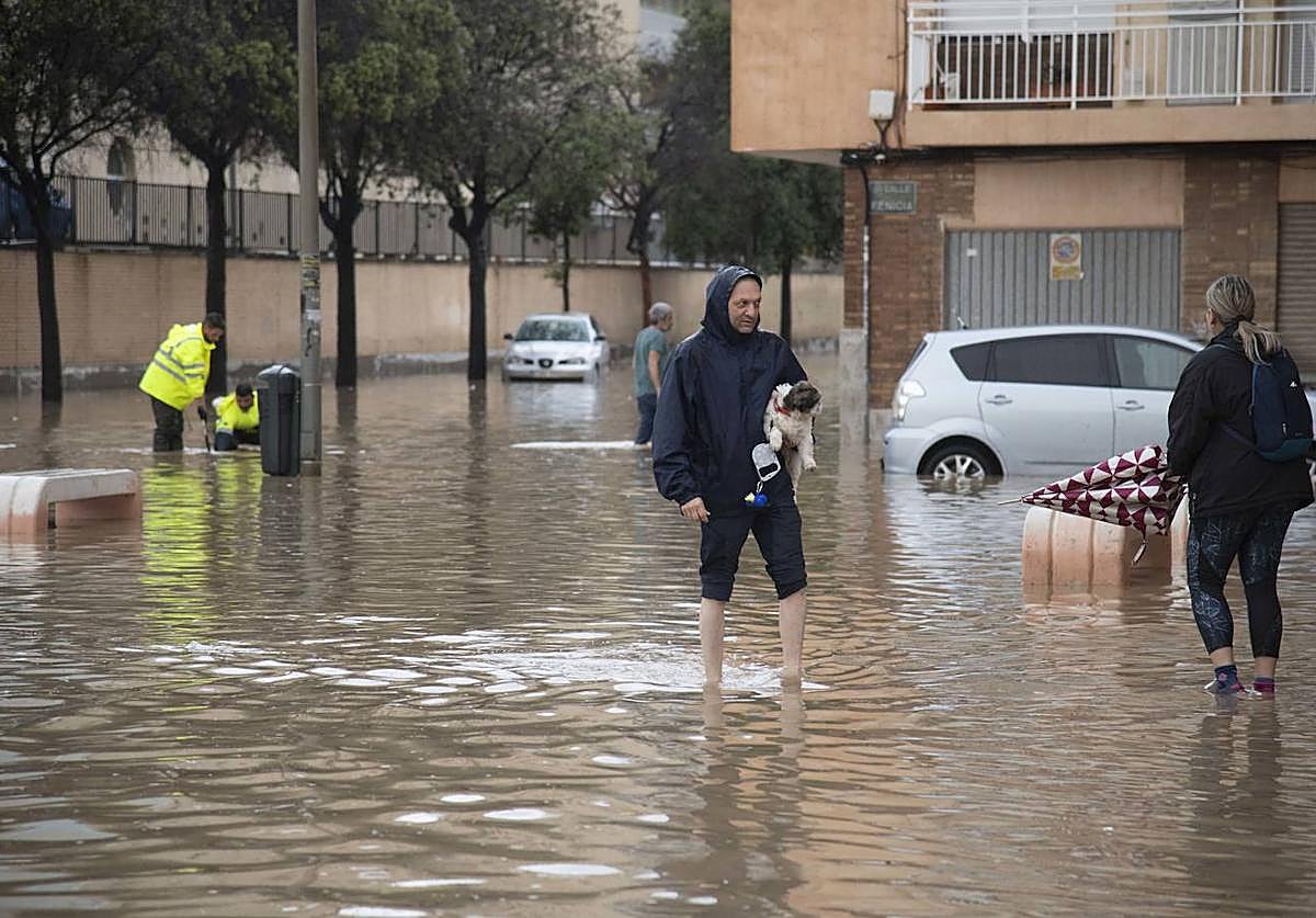 Dos personas cruzan una calle inundada en Cartagena en un día lluvioso del pasado mes de mayo.