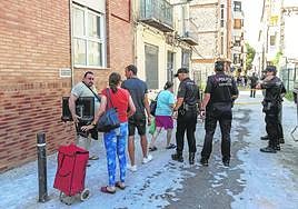 Algunos de los residentes del edificio sacan sus pertenencias vigilados por agentes municipales y nacionales.