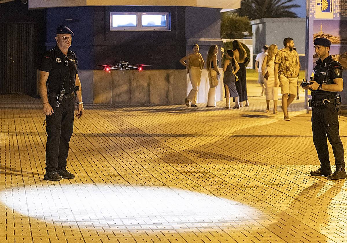 Dos policías, en una plaza de Cabo de Palos, ponen en marcha un dron con el que vigilan las zonas donde se concentran jóvenes.