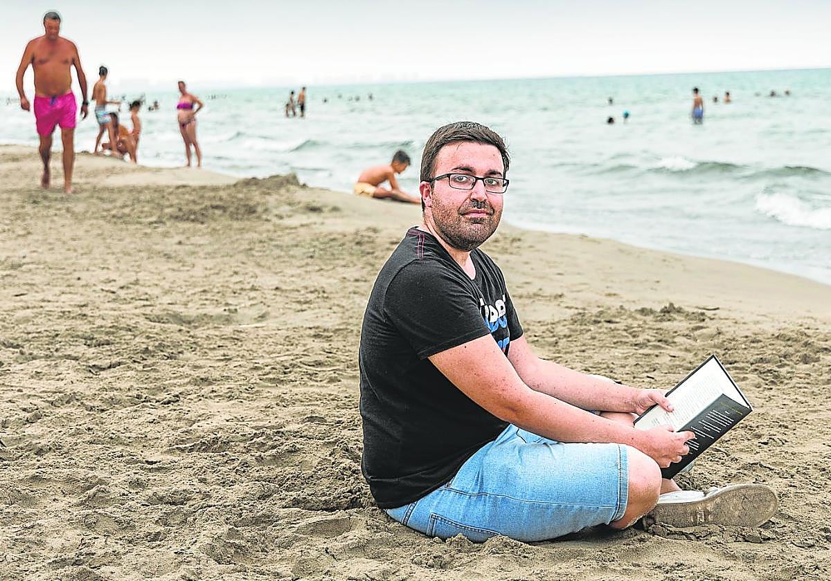 Rubén Martínez se dispone a disfrutar de su libro en la playa Manga Beach, de La Manga del Mar Menor.