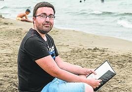 Rubén Martínez se dispone a disfrutar de su libro en la playa Manga Beach, de La Manga del Mar Menor.