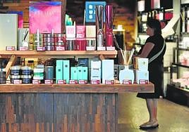 Una mujer examina los precios de los productos en rebajas en una tienda de cosméticos.