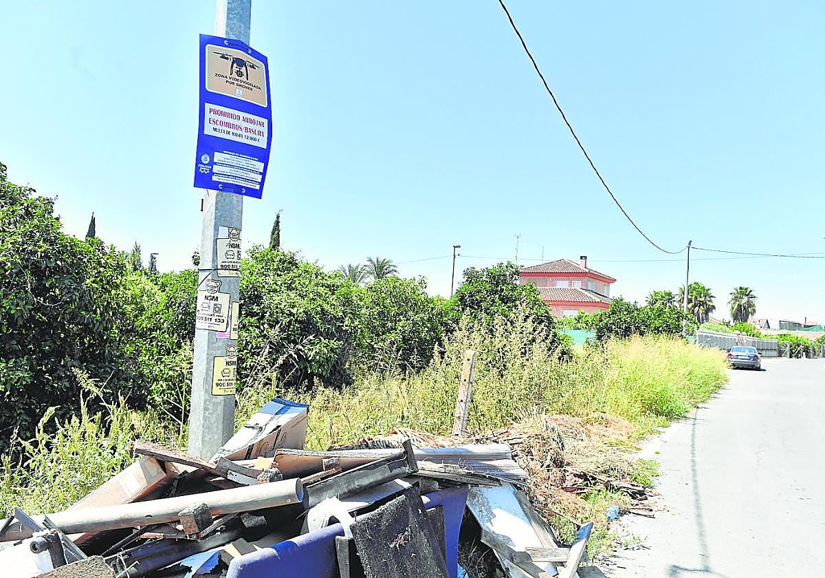 Enseres y otros restos depositados justo debajo de un cartel de área vigilada con drones para evitar vertidos.