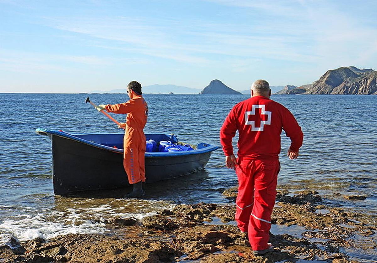 Un operario y un trabajador de Cruz Roja revisan la zona a la que ha llegado una patera, en una imagen de archivo.