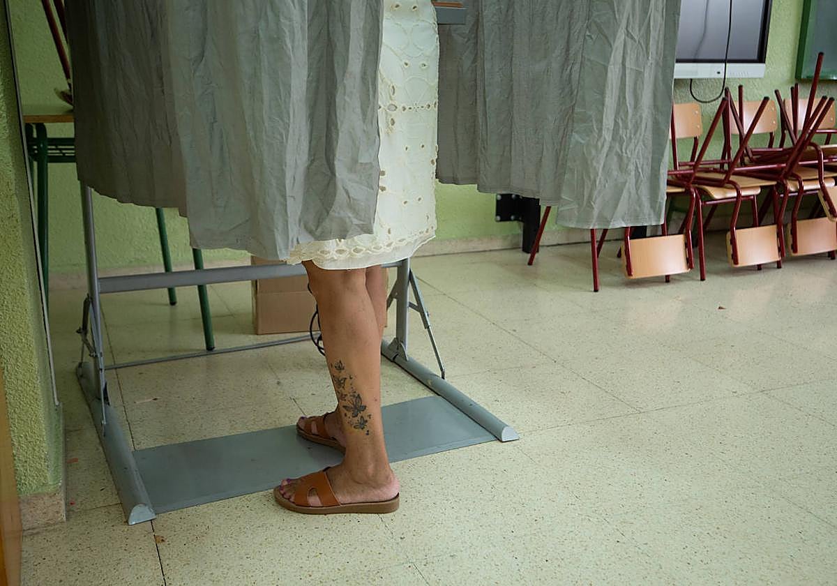 Una ciudadana selecciona las papeletas que va a introducir en las urnas en Murcia durante el 23-J.