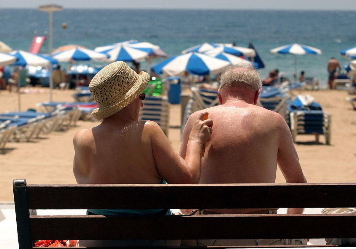 Una pareja de turistas junto a la playa, en una imagen de archivo.