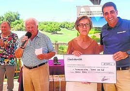 Ascensión Méndez recibe el cheque del Banco Mediolanum, mientras Pedro Jiménez se dirige a los presentes y Joaquín Madrid aplaude.