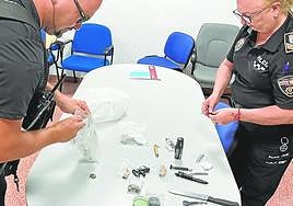 Dos agentes inspeccionan objetos hallados.