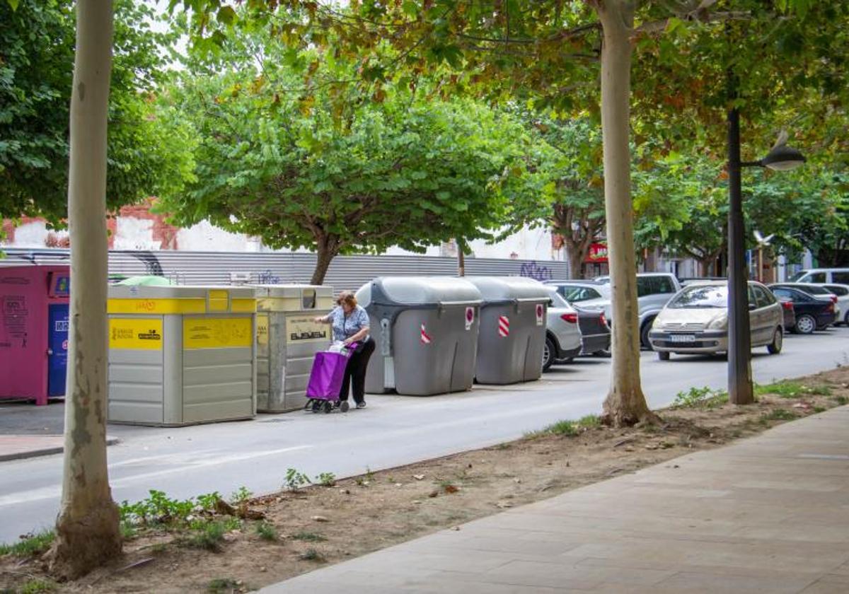 Una mujer deposita residuos plásticos en un contenedor amarilla de los Andenes, en Orihuela.