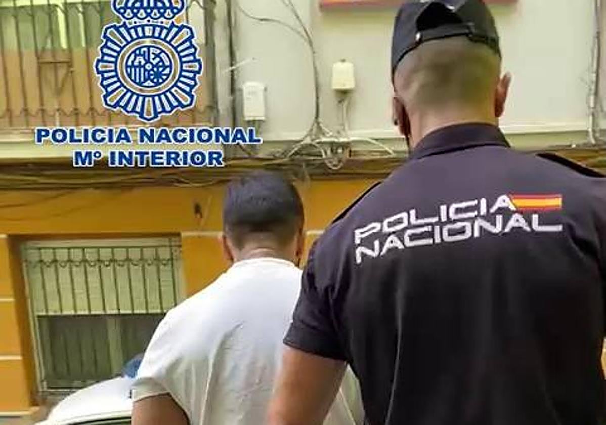 Un agente conduce a uno de los detenidos al coche policial
