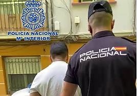 Un agente conduce a uno de los detenidos al coche policial