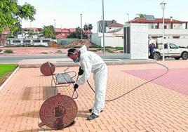 Un técnico pulveriza con larvicida una alcantarilla.