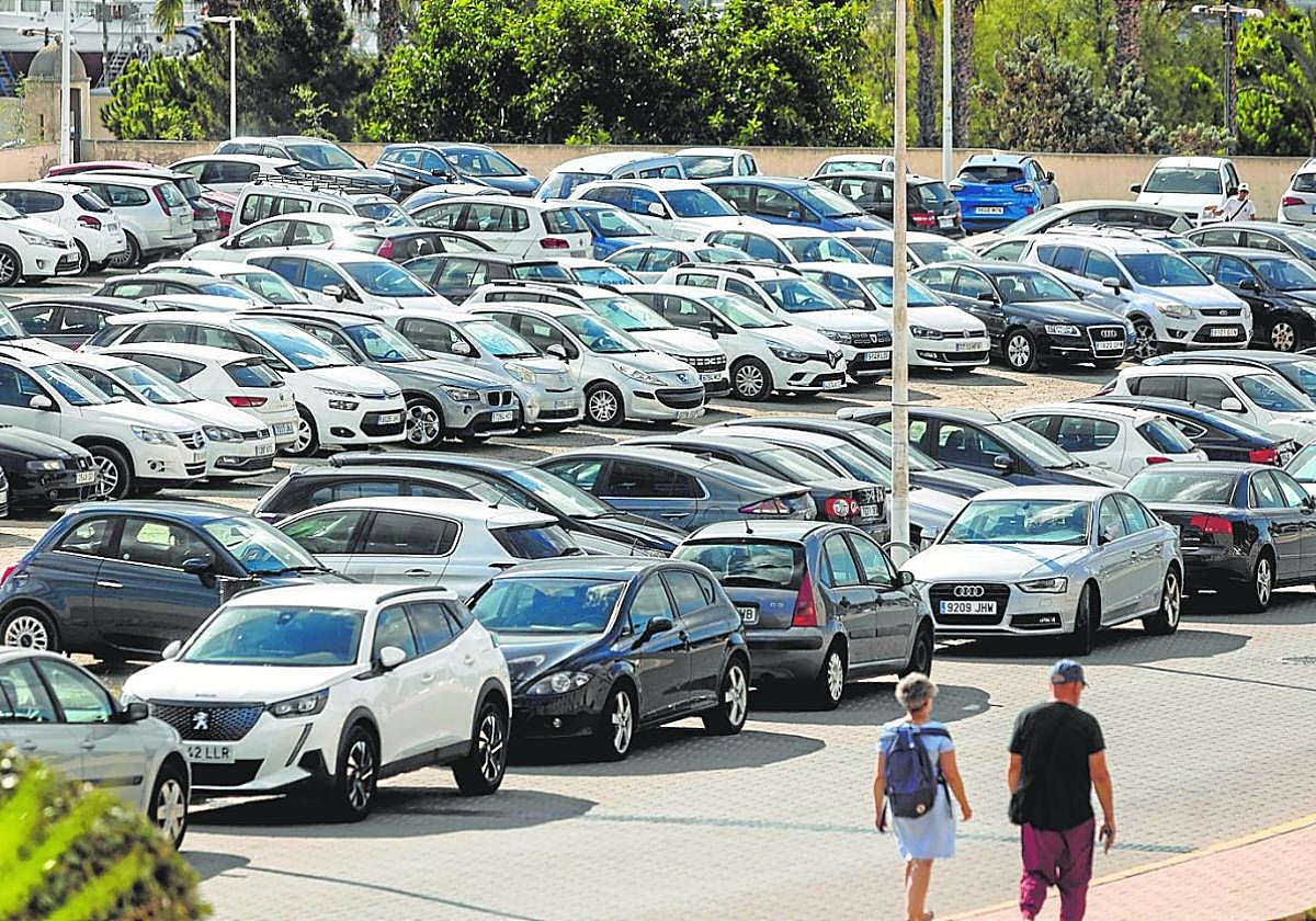 Dos personas caminan junto a un solar repleto de coches en el campus de la Muralla del Mar ayer por la mañana.