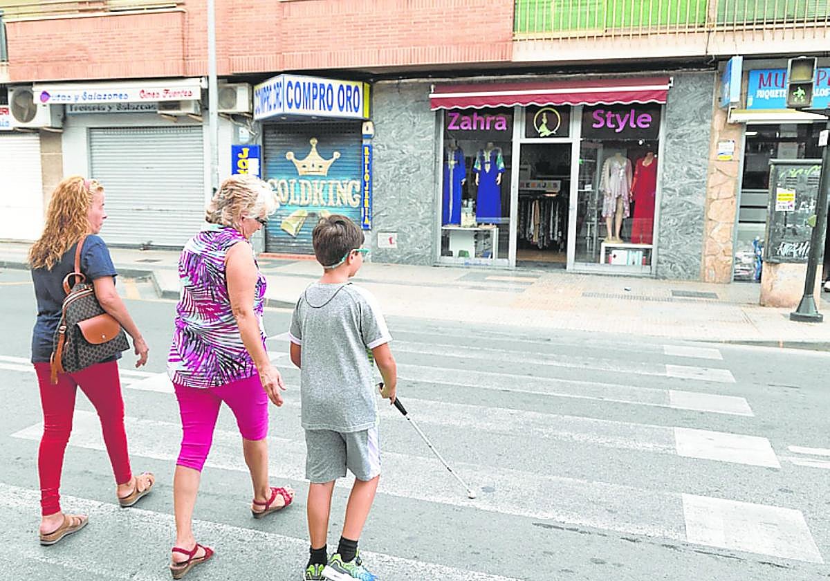 Andrés Ros cruza por un paso de peatones en Los Dolores acompañado de su tía Raquel Teruel y de su vecina Bienvenida Molero.