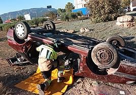 Un bombero trabaja en el coche volcado de Alhama.