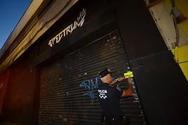 Un agente de la Policía Local fija el precinto en la entrada de la sala Spectrum, en la zona de Mariano Rojas de Murcia.