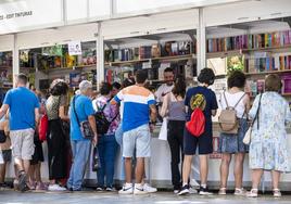 Visitantes ojean los libros de las casetas en el Paseo Alfonso X el Sabio.