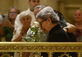 La familiar de uno de los fallecidos llora desconsolada con la rosa blanca que le entregó el obispo.