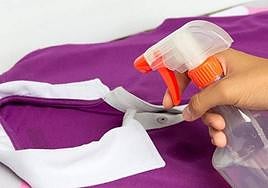 Una persona pulveriza un líquido sobre una prenda de ropa.