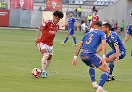 Carlos Rojas controla el balón ante dos adversarios.