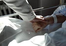 Un sanitario sostiene la mano de un paciente en una imagen de archivo.