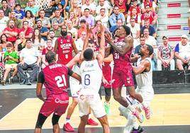 Dylan Ennis, rodeadode rivales, se dispone alanzar a canasta en elUCAM-Unicaja de laSupercopa.