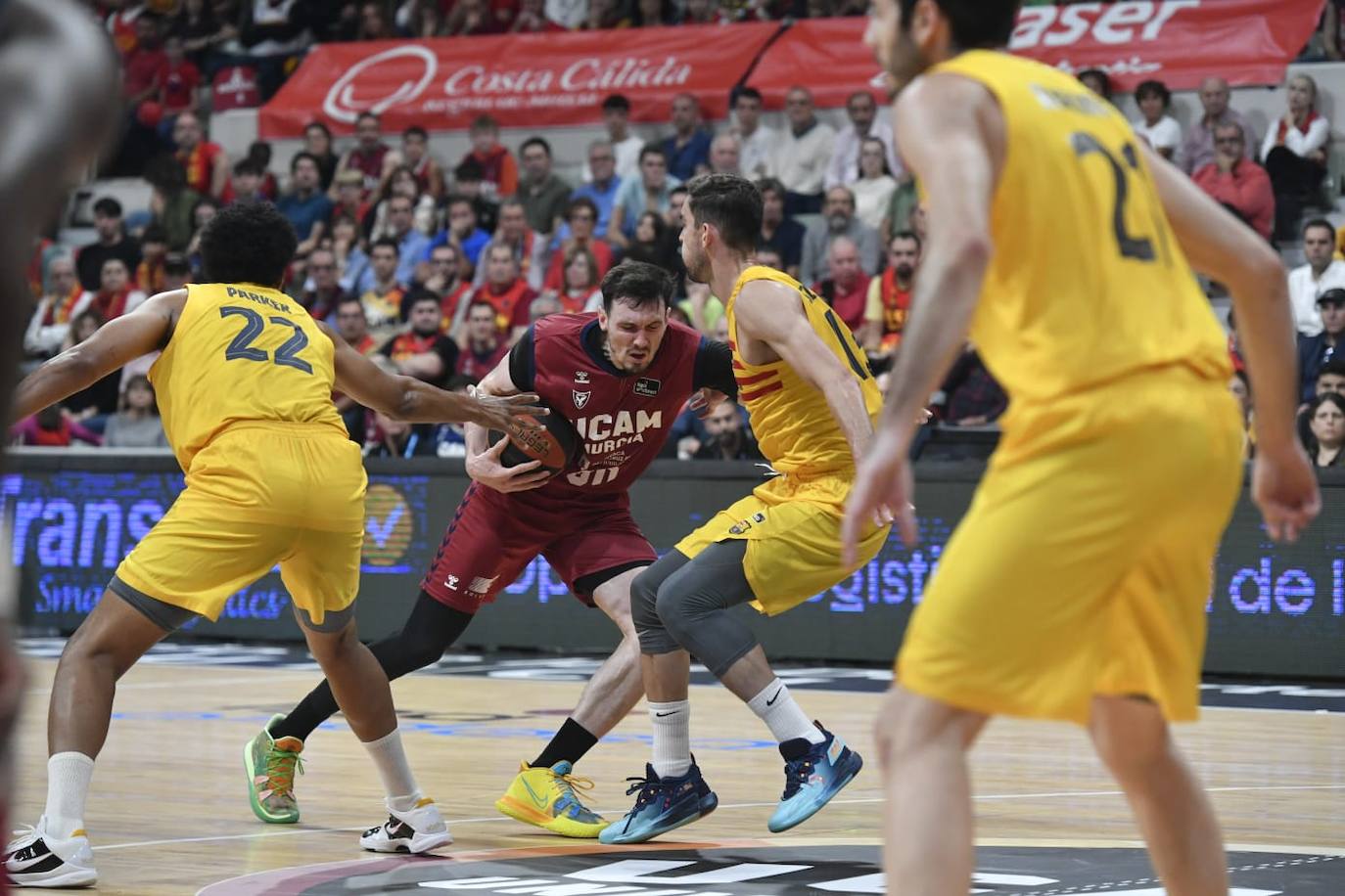 Jugadores del Barça tratan de arrebatarle el balón al UCAM.