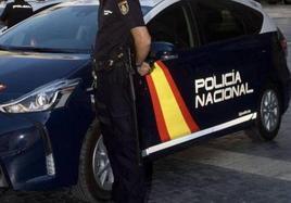 Un agente de la Policía Nacional junto a un coche patrulla, en una imagen de archivo.