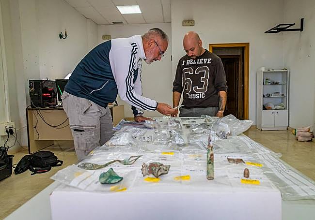 Balas, cubiertos e insignias se mezclan sobre la mesa de estudio.