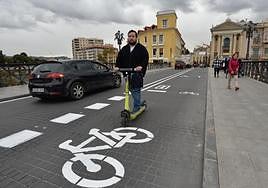 Un joven circula con un patinete de alquiler sobre el nuevo tramo de carril bici trazado desde ayer sobre el Puente de los Peligros.