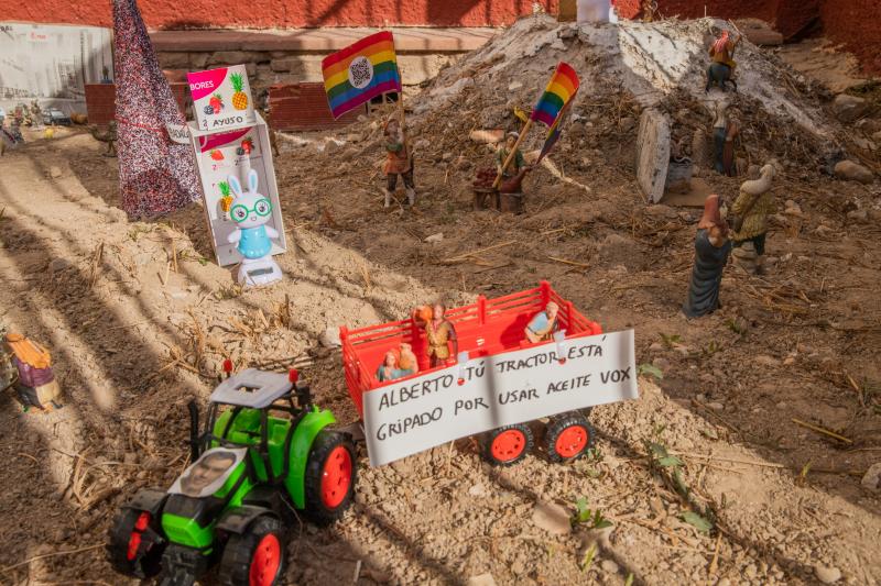 Un tractor con la imagen del presidente del Gobierno, Pedro Sánchez, lleva un remolque con la frase que le dedicó el portavoz del PNV en el Congreso, Aitor Esteban, al líder del PP, Alberto Núñez Feijóo. Al fondo, la presidenta de la Comunidad de Madrid, Isabel Díaz Ayuso, sobre fondo frutal y el árbol de Navidad de Badalona, que compite este año con el de Vigo por ser el más grande.