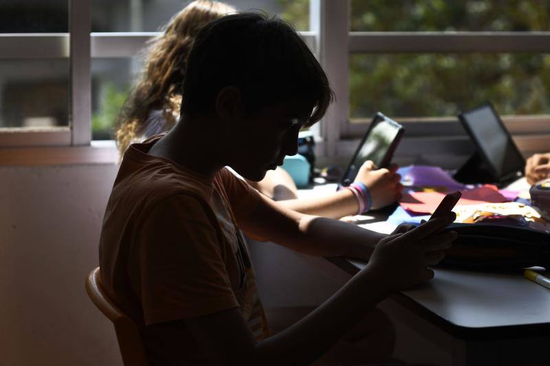 Imagen de archivo de un estudiante usando el móvil en clase.