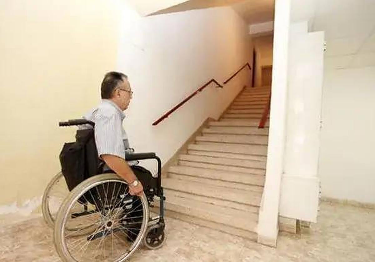 Un hombre en silla de ruedas no puede subir las escaleras de una vivienda, en una imagen de archivo.