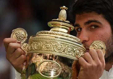 Carlos Alcaraz besa el trofeo de campeón del torneo de Wimbledon.