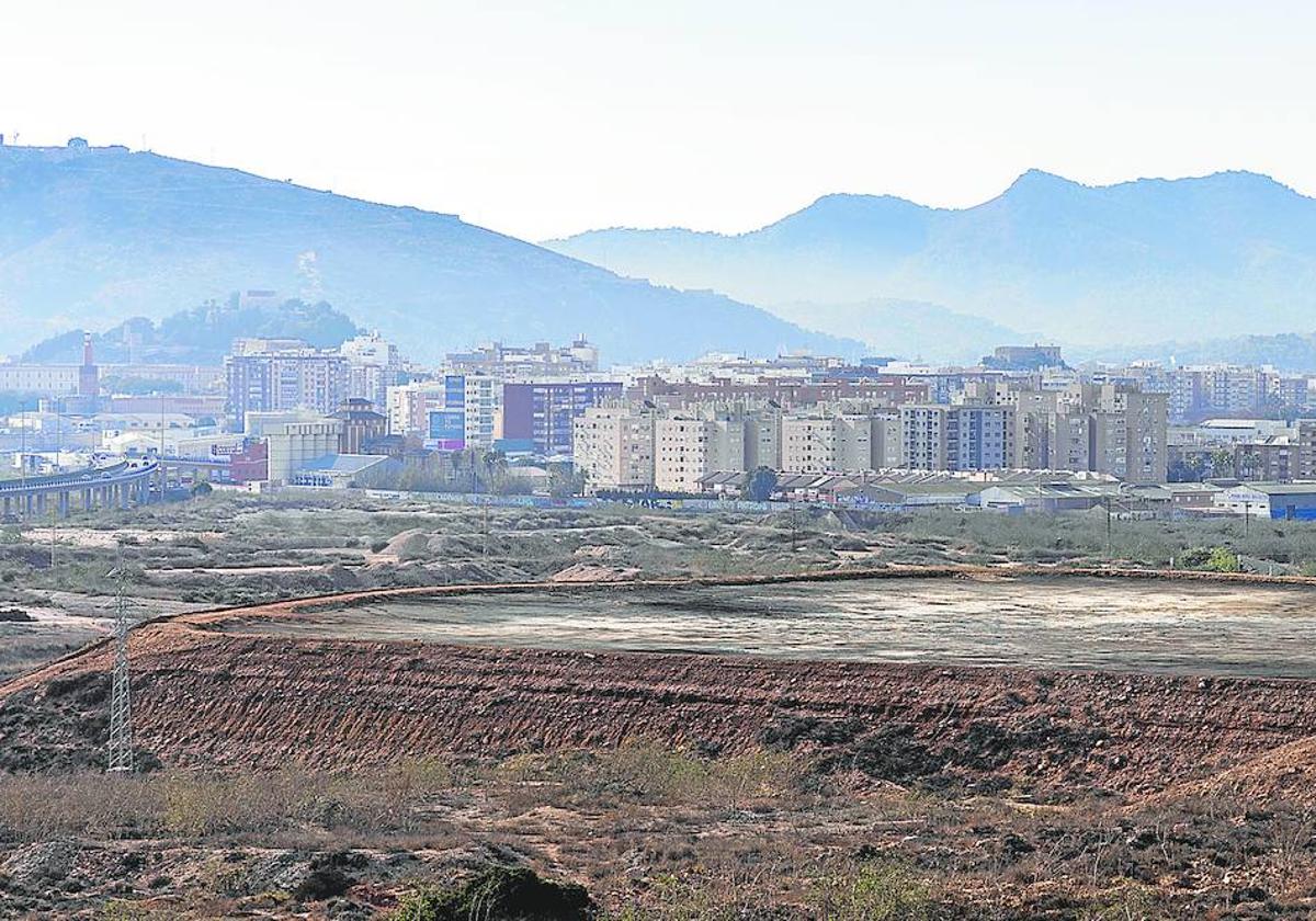 Una de las cinco balsas con metales pesados sin cubrir de la antigua factoría Zinsa, con las primeras viviendas de la ciudad en segundo término.