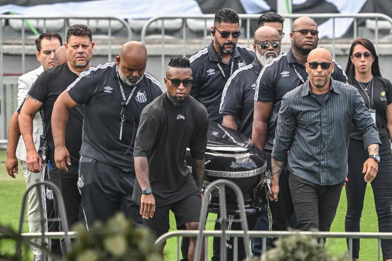 Un grupo de personas, encabezado por uno de los hijos de Pelé, Edinho, transportan su ataúd al estadio del Santos. 