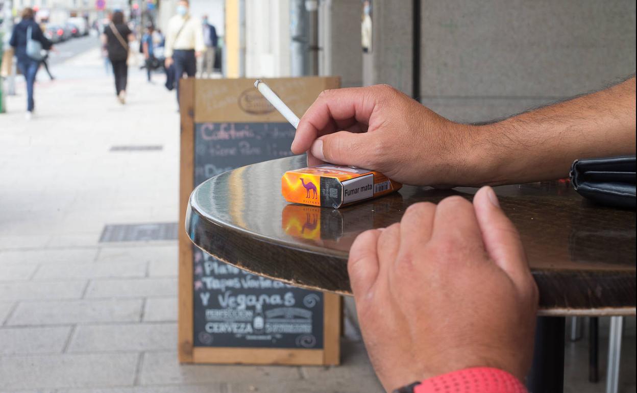 Un hombre fuma en la terraza de un bar.