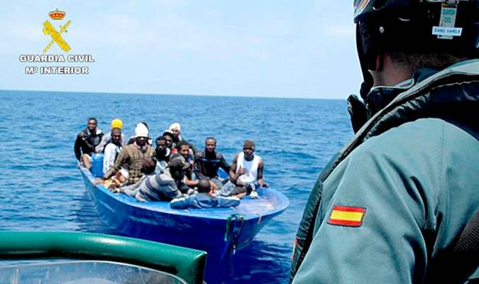 Un agente de la Guardia Civil vigila una patera con inmigrantes que ha sido interceptada en aguas del Estrecho.