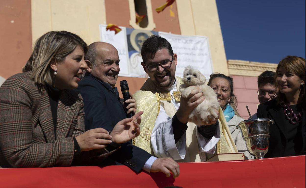 El párroco sostiene a un cachorro durante la celebración.