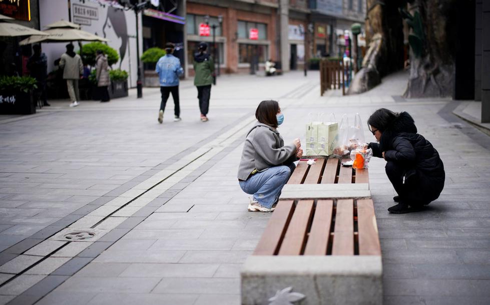 Dos mujeres comen en una zona comercial de la ciudad.