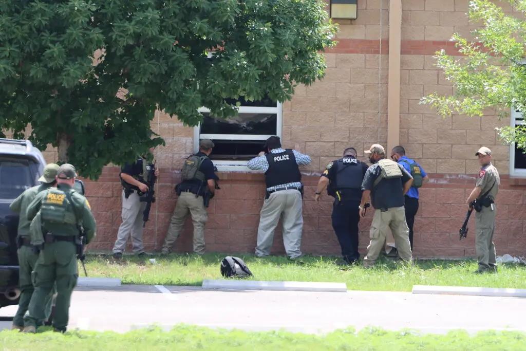 Un grupo de policías observa el interior del colegio de Uvalde, indeciso a entrar en su interior. 