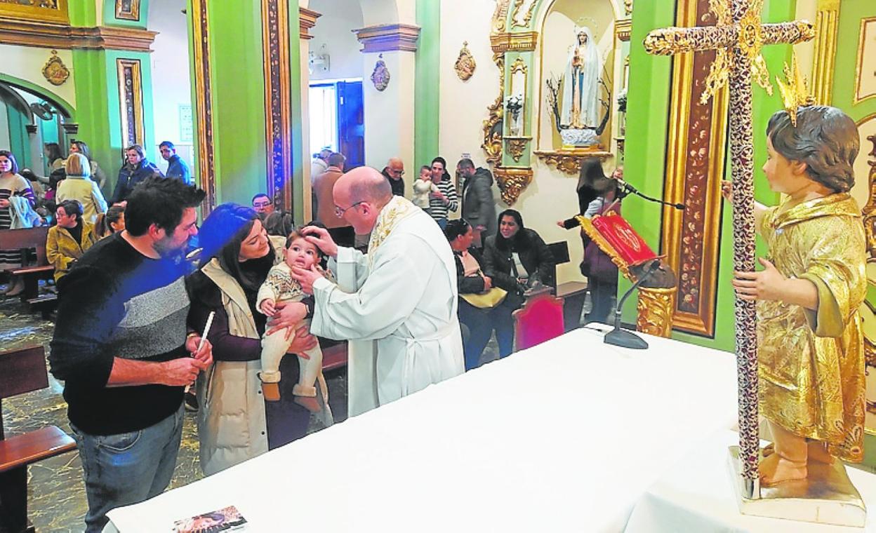 El párroco bendice a uno de los niños ante la imagen sagrada. 