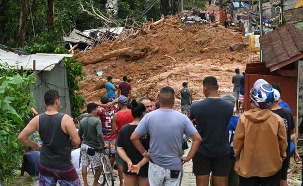 Un grupo de vecinos miran una calle cubierta de lodo en Sao Sebastiao tras las inundaciones