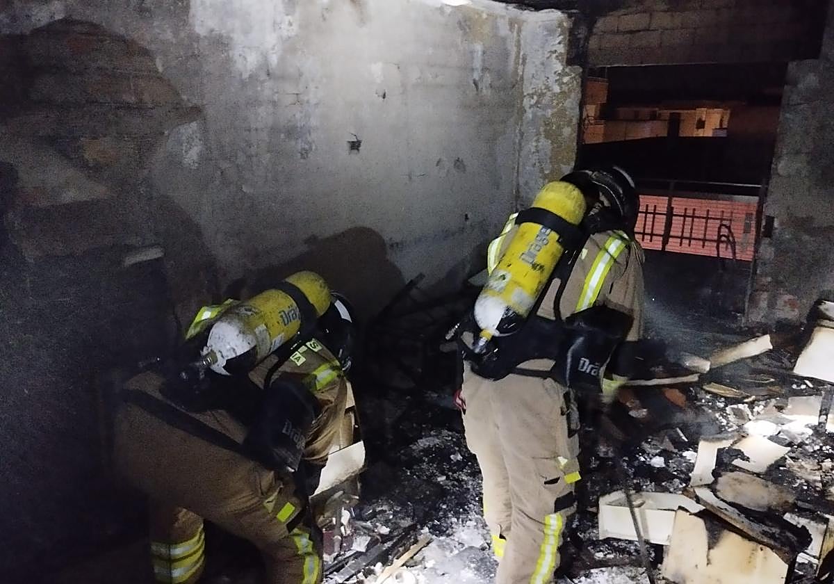 Los bomberos en la vivienda calcinada.