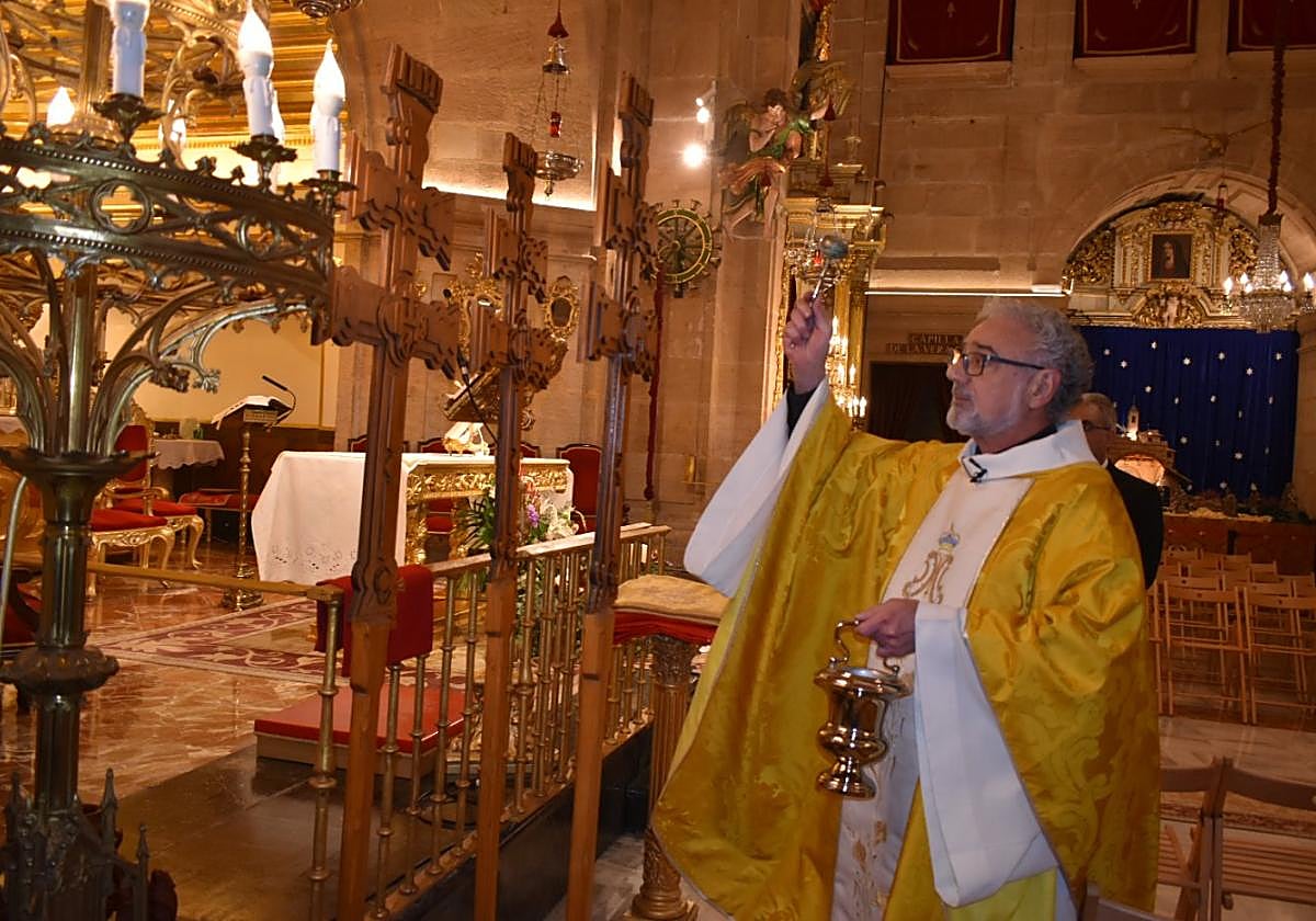 El rector de la basílica, Emilio Andrés Sánchez Espín, bendice las nuevas cruces para los grupos de peregrinos.
