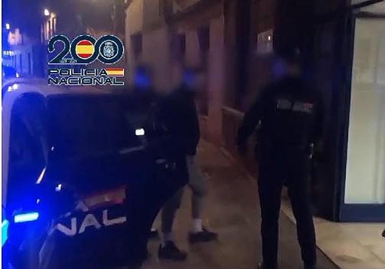 Dos agentes de la policía arrestan a uno de los culpables.