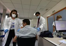 Dos enfermeros administran las vacunas de la gripe y covid a un paciente en Murcia, en octubre.