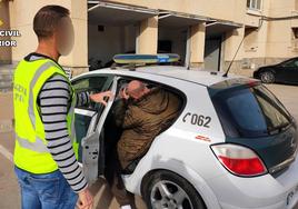 Un Guardia Civil introduce a un integrante de la banda detenida en el coche.