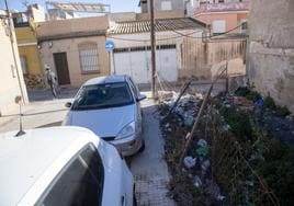 Un hombre pasea por la calle Portlant, en el Barrio de La Concepción, con un solar lleno de basura y maleza a la derecha.