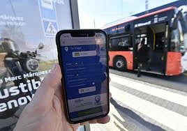 Un móvil muestra el modelo de aplicación usado en otras ciudades y que se empleará en Murcia, frente a un bus de Monbus.